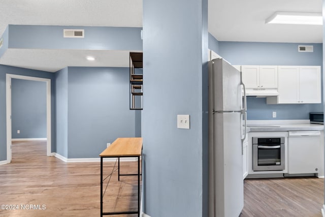 kitchen featuring white cabinets, stainless steel appliances, and light wood-type flooring