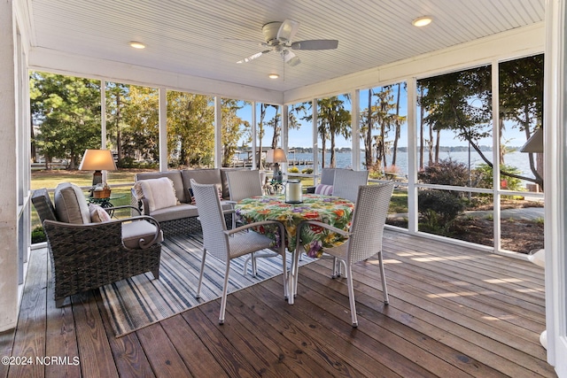 sunroom / solarium with a water view, ceiling fan, and a wealth of natural light