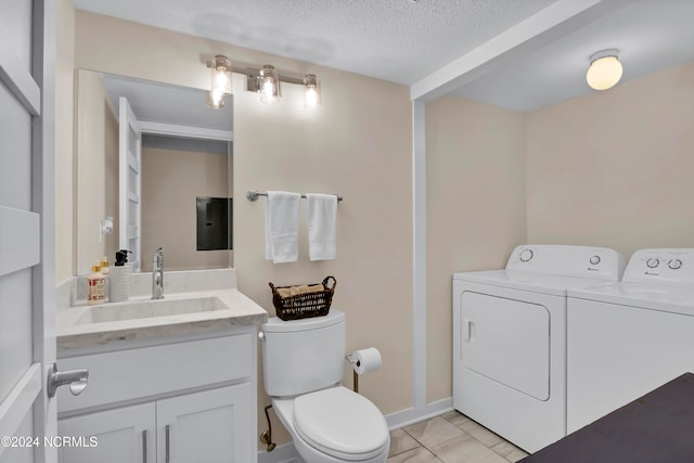 bathroom with vanity, baseboards, a textured ceiling, toilet, and washing machine and dryer