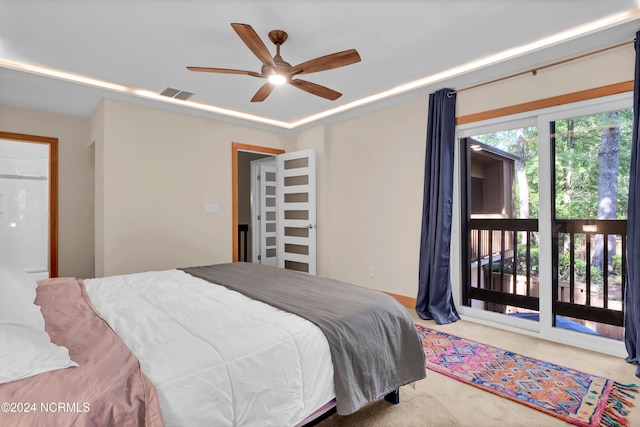 carpeted bedroom featuring a tray ceiling, access to exterior, visible vents, and ceiling fan