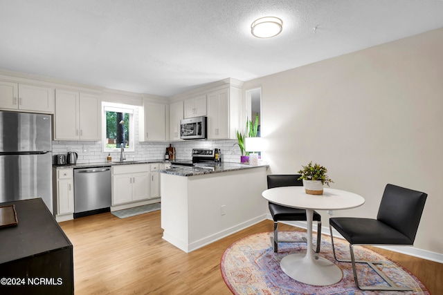 kitchen with sink, white cabinets, stainless steel appliances, and light wood-type flooring