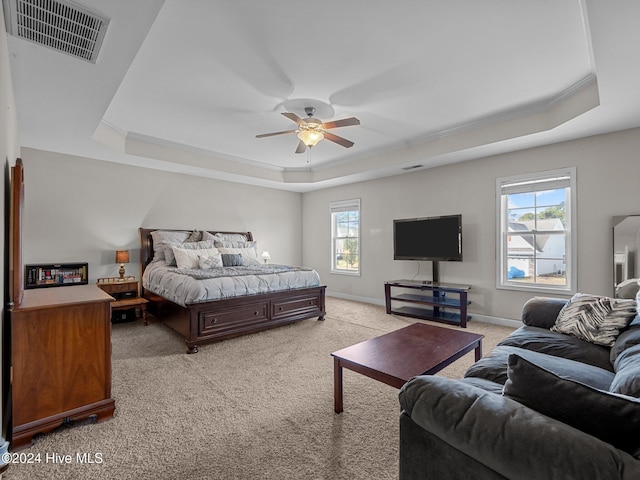 carpeted bedroom with a raised ceiling, multiple windows, and ceiling fan