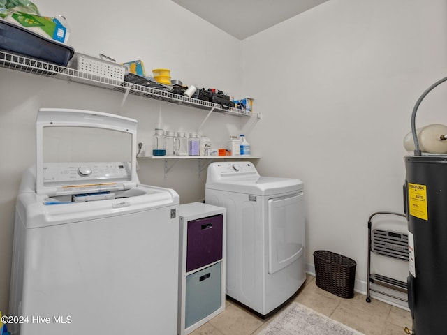 clothes washing area featuring water heater, light tile patterned floors, and washing machine and clothes dryer