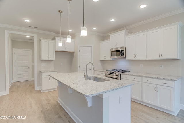 kitchen featuring sink, white cabinetry, light hardwood / wood-style floors, stainless steel appliances, and a center island with sink