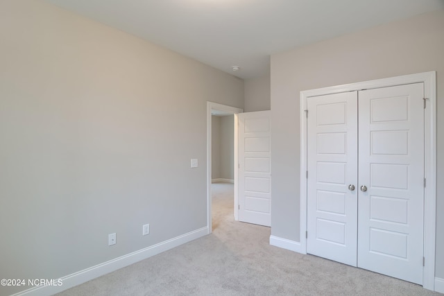 unfurnished bedroom featuring light carpet and a closet