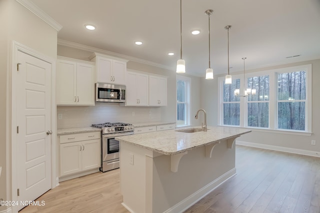 kitchen with white cabinets, stainless steel appliances, sink, and an island with sink