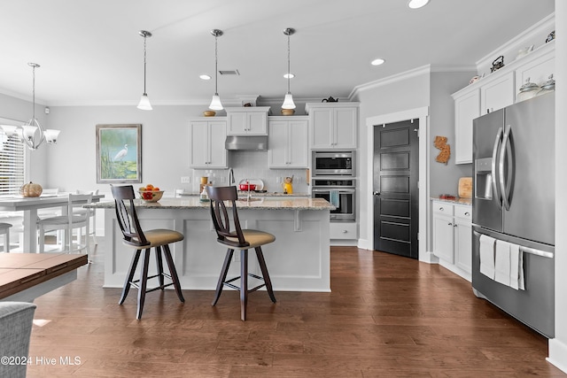 kitchen featuring hanging light fixtures, a center island with sink, appliances with stainless steel finishes, a breakfast bar, and white cabinetry