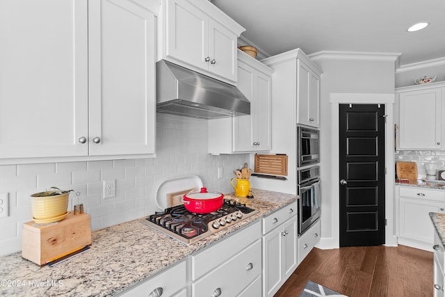 kitchen featuring dark hardwood / wood-style floors, stainless steel appliances, crown molding, white cabinets, and tasteful backsplash