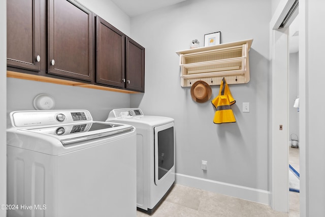 clothes washing area with cabinets and washing machine and dryer