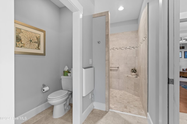 bathroom with a tile shower, toilet, and tile patterned flooring