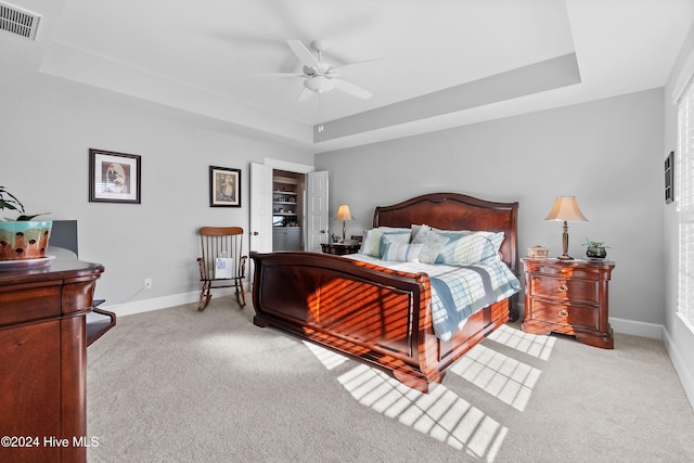 bedroom featuring ceiling fan, light carpet, and a raised ceiling