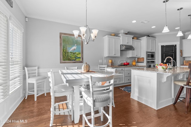 kitchen featuring dark hardwood / wood-style flooring, decorative light fixtures, a kitchen breakfast bar, and a kitchen island with sink