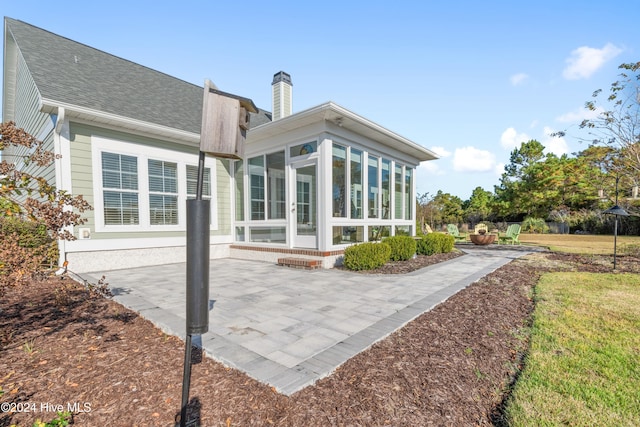 rear view of house with a patio area, a lawn, and a sunroom