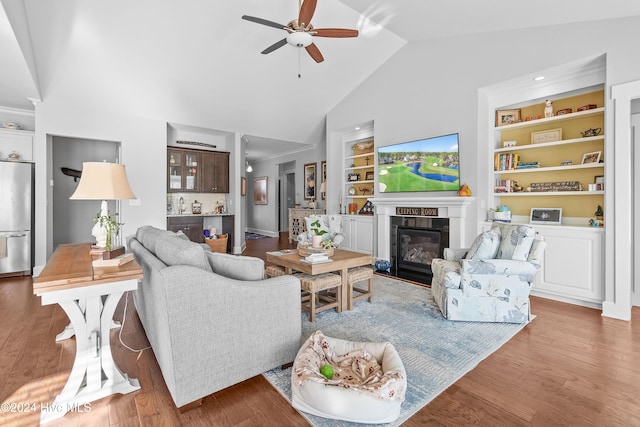 living room with hardwood / wood-style flooring, ceiling fan, built in features, and vaulted ceiling