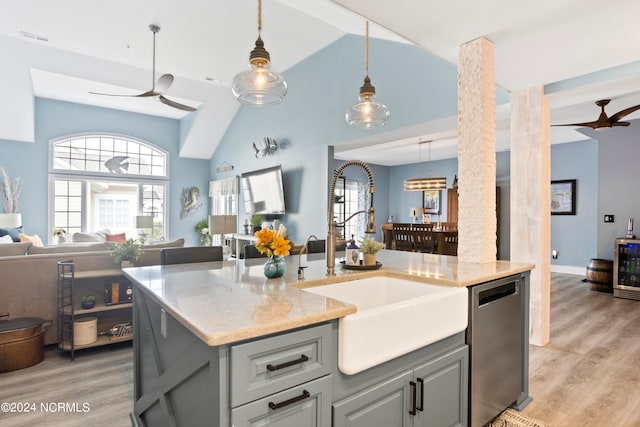 kitchen with sink, an island with sink, light hardwood / wood-style floors, decorative light fixtures, and stainless steel dishwasher