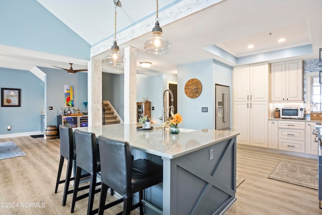 kitchen with light hardwood / wood-style flooring, light stone counters, stainless steel appliances, and decorative light fixtures