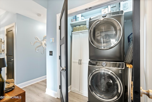 laundry area with light hardwood / wood-style floors and stacked washer / drying machine