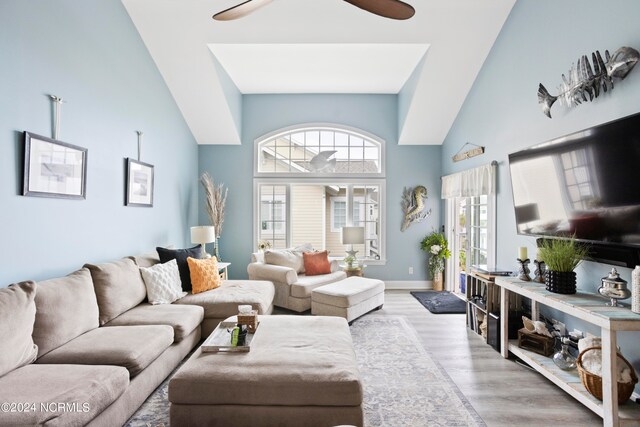 living room featuring a high ceiling, light hardwood / wood-style floors, and ceiling fan