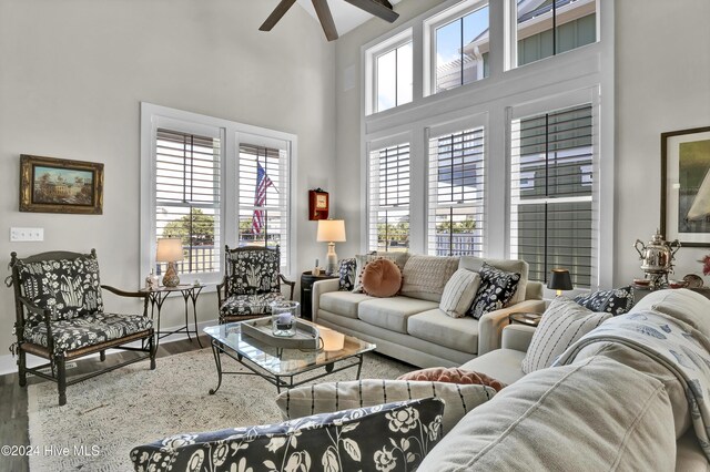 living room featuring beamed ceiling, wood-type flooring, ceiling fan, and a high ceiling