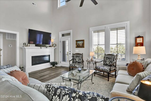 living room featuring a wealth of natural light, hardwood / wood-style floors, a towering ceiling, and ceiling fan