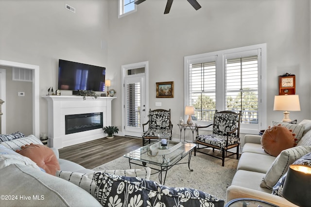 living room featuring ceiling fan, visible vents, wood finished floors, and a glass covered fireplace