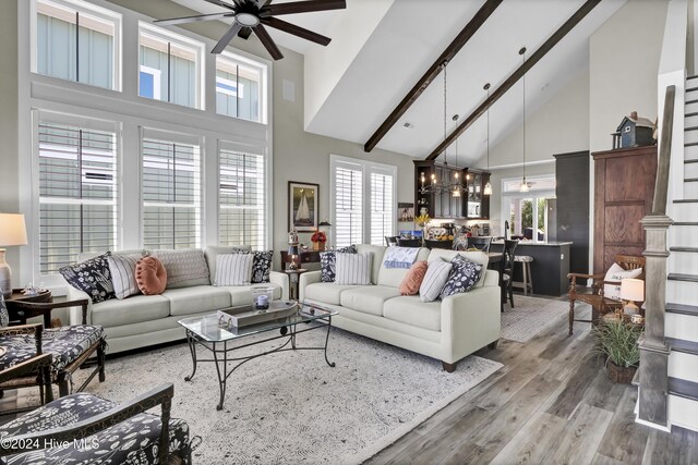 living room with ceiling fan with notable chandelier, beam ceiling, wood-type flooring, and high vaulted ceiling