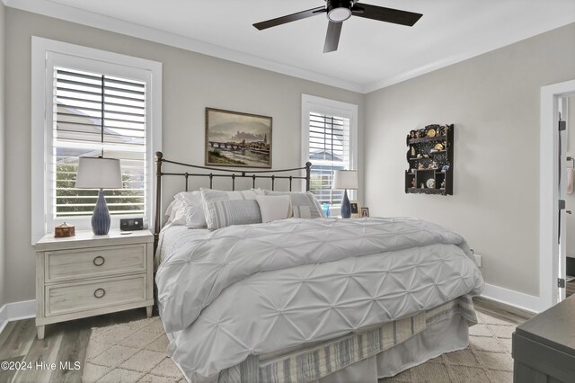 bedroom with ceiling fan, light hardwood / wood-style floors, and multiple windows