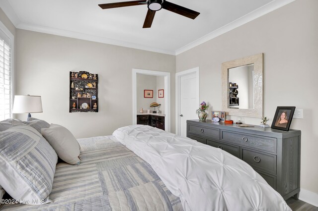 bedroom with ceiling fan, crown molding, ensuite bathroom, and wood-type flooring