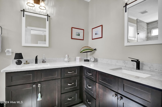 full bath featuring double vanity, visible vents, and a sink