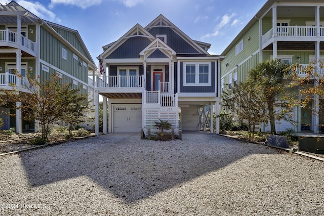 raised beach house with a garage, a carport, and gravel driveway