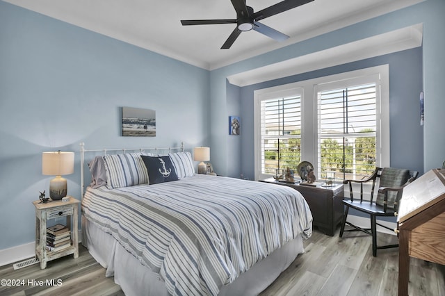 bedroom featuring crown molding, visible vents, a ceiling fan, wood finished floors, and baseboards