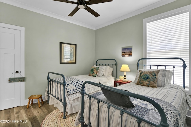 bedroom with ceiling fan, wood finished floors, and crown molding