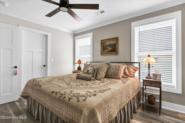 bedroom with ornamental molding, dark wood-type flooring, visible vents, and baseboards