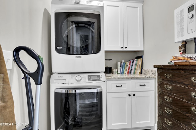 laundry room with stacked washer and clothes dryer and cabinet space