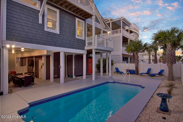 pool at dusk with a patio and an outdoor hangout area