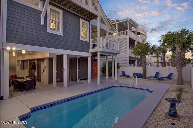 pool at dusk with a patio area, fence, and a fenced in pool