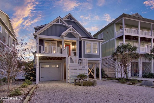 coastal home featuring a garage, stairs, board and batten siding, and gravel driveway