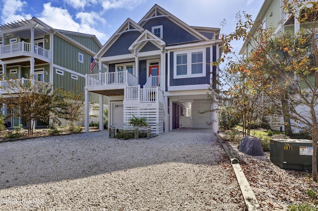 coastal home featuring a garage, board and batten siding, and gravel driveway