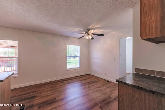 unfurnished living room featuring a textured ceiling, a healthy amount of sunlight, and dark hardwood / wood-style flooring