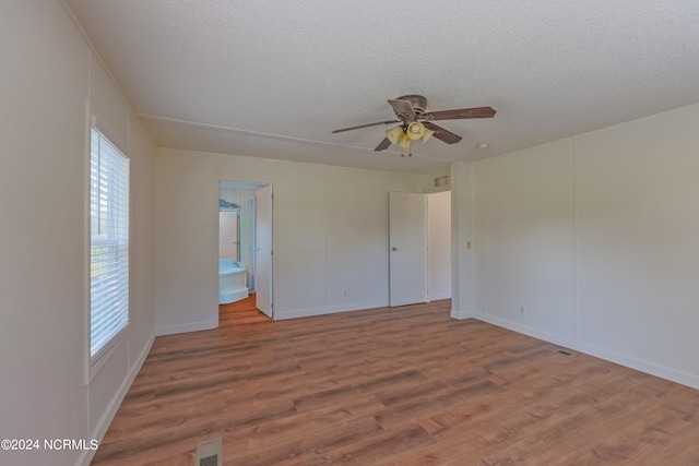 spare room with ceiling fan, a textured ceiling, and light wood-type flooring