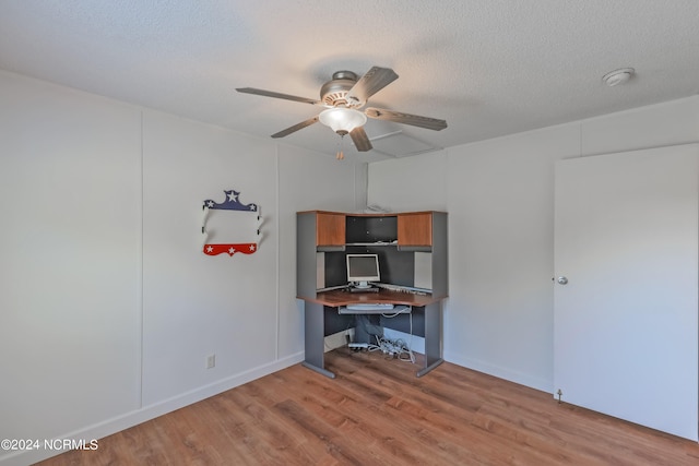 home office featuring built in desk, ceiling fan, a textured ceiling, and light wood-type flooring