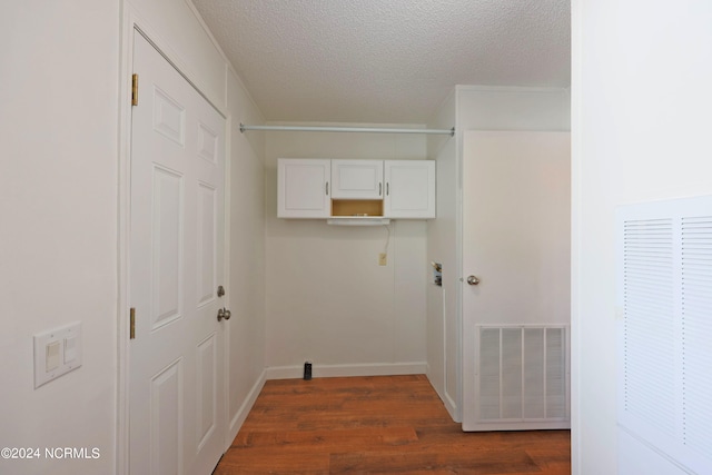 laundry area featuring dark wood-type flooring and a textured ceiling