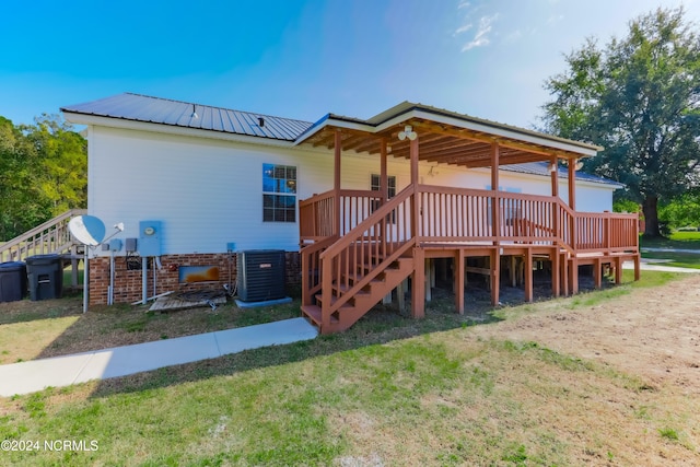 back of house with central AC, a wooden deck, and a lawn