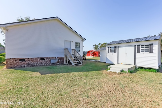 back of house with a yard and a shed