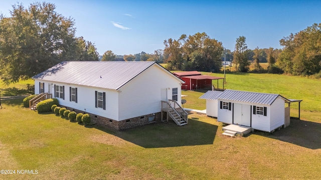 back of house with a storage shed and a lawn