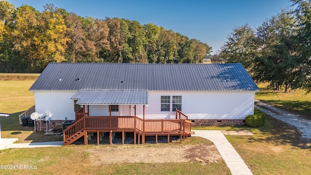 rear view of house featuring a wooden deck and a lawn