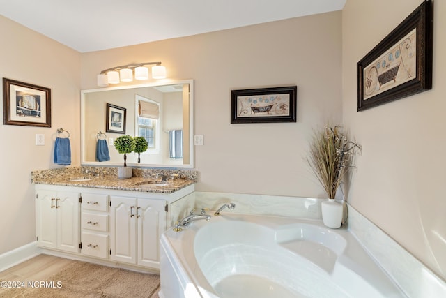 bathroom with hardwood / wood-style flooring, vanity, and a washtub