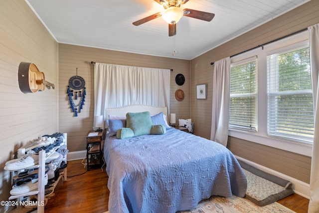 bedroom featuring ceiling fan, wooden walls, and hardwood / wood-style flooring