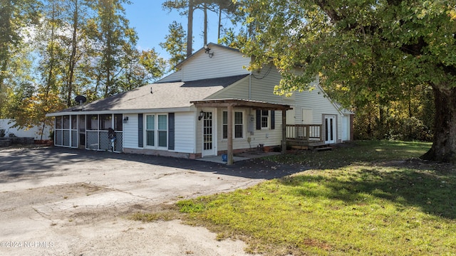 rear view of house featuring a lawn and a sunroom