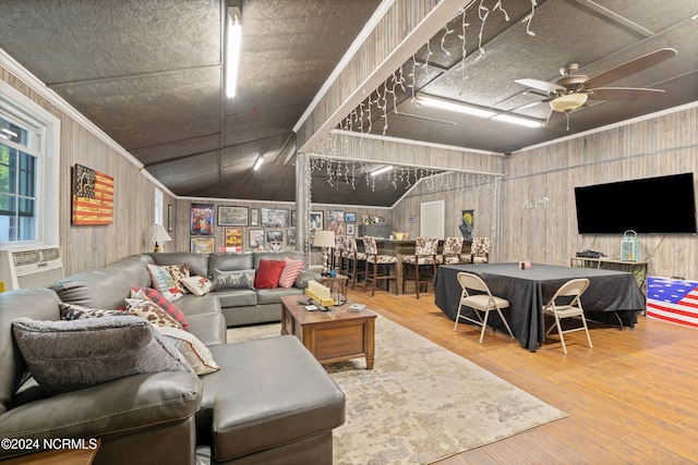 living room featuring wooden walls, ceiling fan, wood-type flooring, and vaulted ceiling